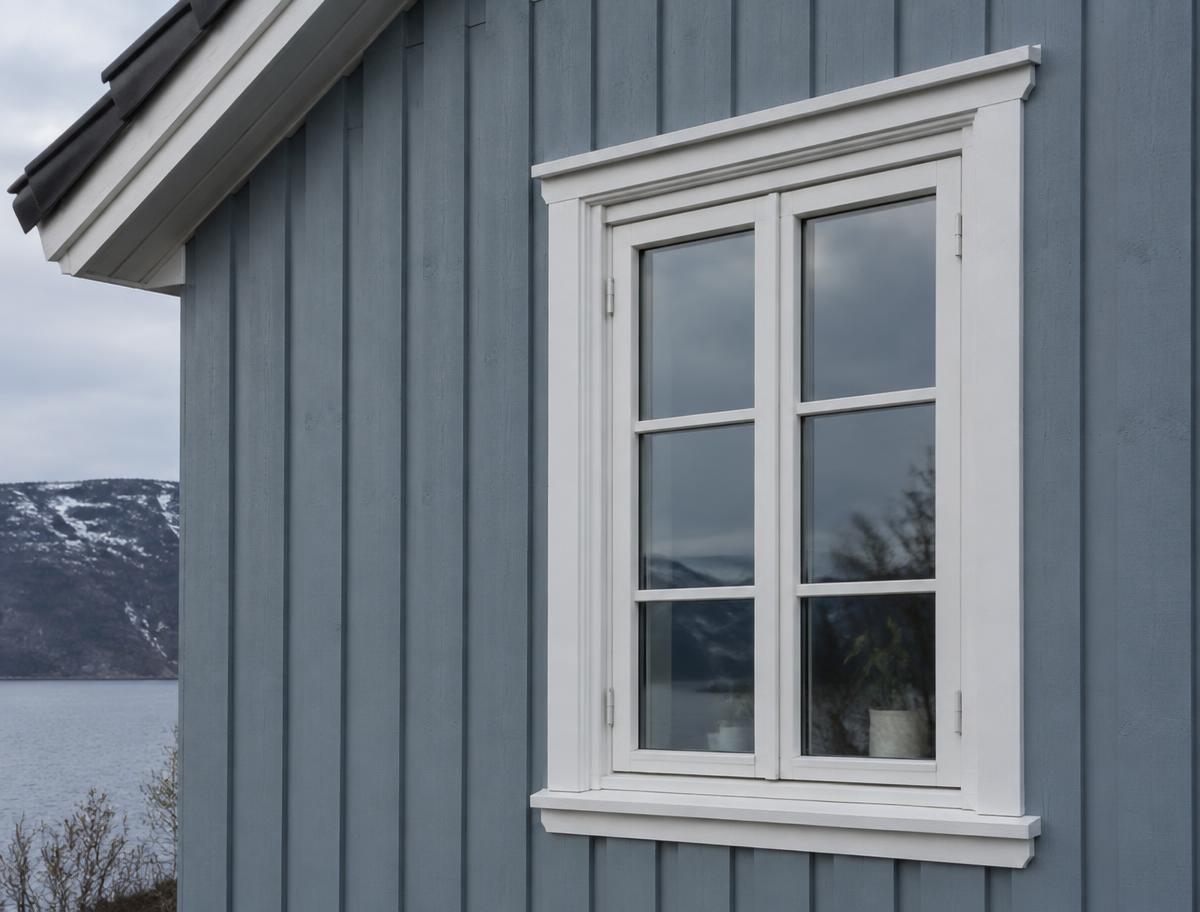 Malt trekledning og hvitt vindusomramming på norsk hus